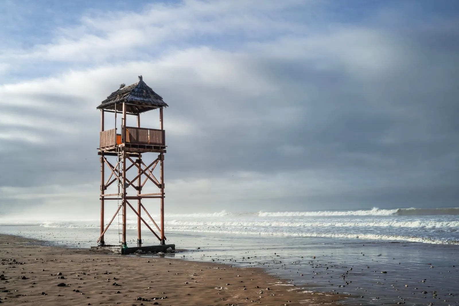 Wieża ratownika na pustej plaży w Agadirze pod zachmurzonym niebem