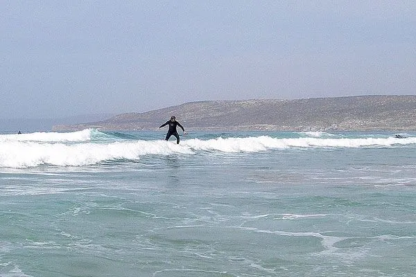 Surfer na fali przy piaszczystym wybrzeżu oceanu