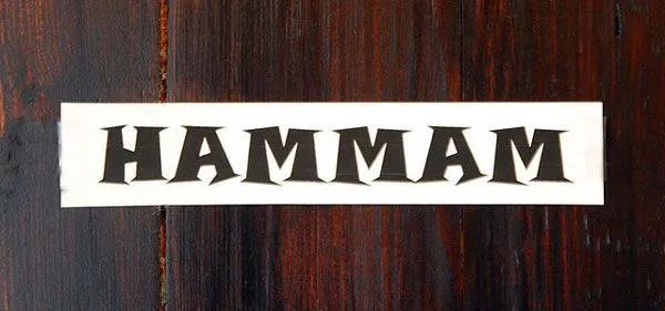 Napis HAMMAM na drewnianej ścianie
